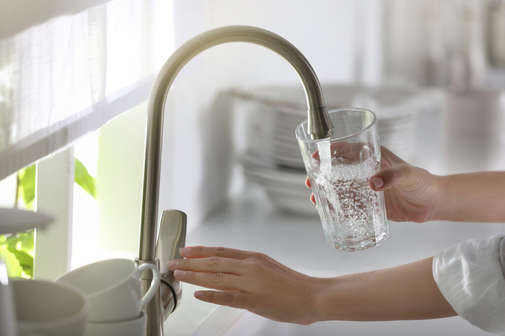 woman pouring water from her reverse osmosis filter into a glass